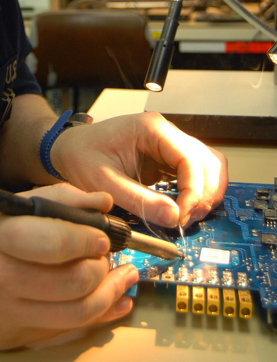 Close-up of hands soldering a component onto a circuit board